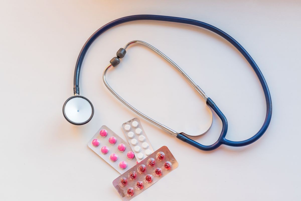 Closeup stethoscope near capsules in blister pack on white table.Top view. drug and pills with phonendoscope. Health care concept